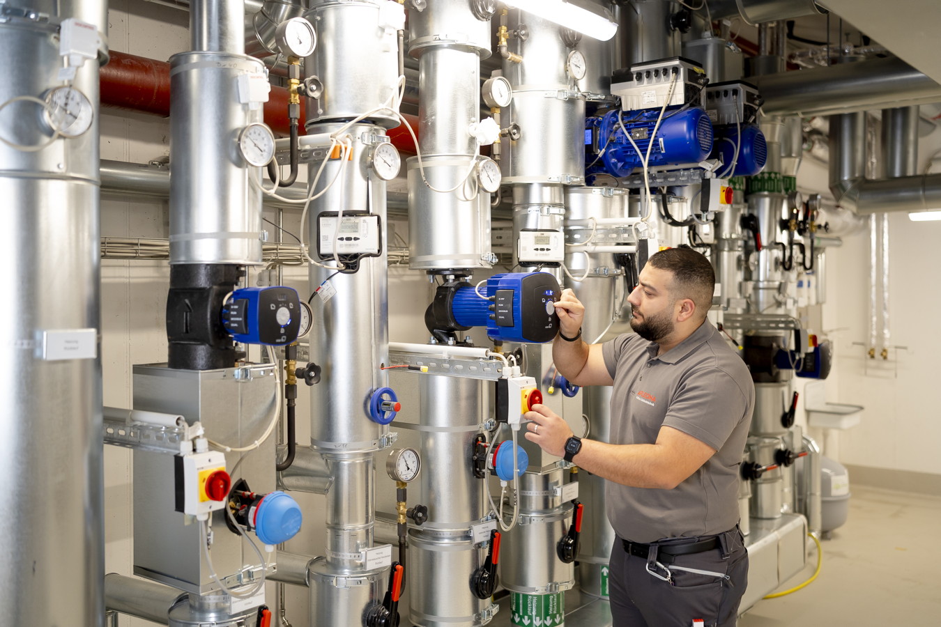 Techniker prüft und stellt eine industrielle Rohrleitungsanlage mit Ventilen und Messgeräten ein