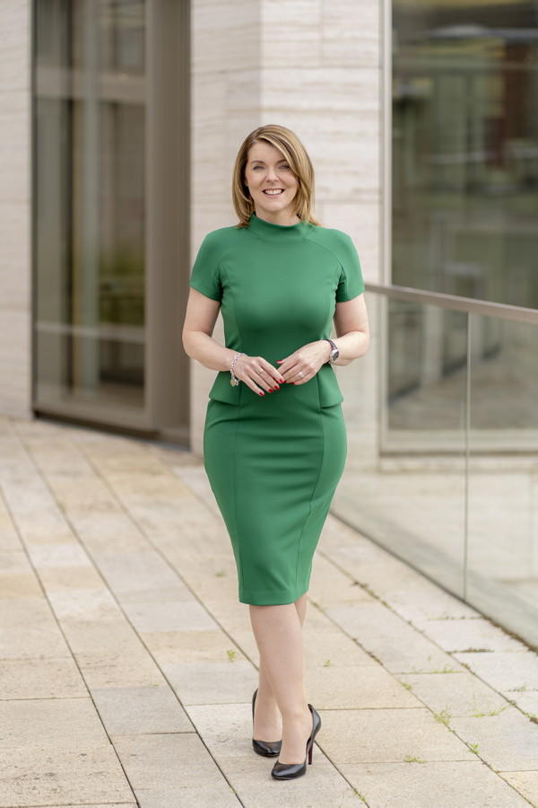 Eine Frau in einem grünen Kleid steht vor einem modernen Gebäude