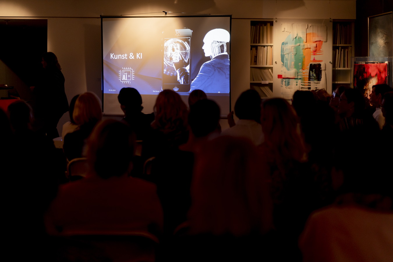 Vortrag vor Publikum mit einer Präsentation „Kunst & KI“ auf der Leinwand
