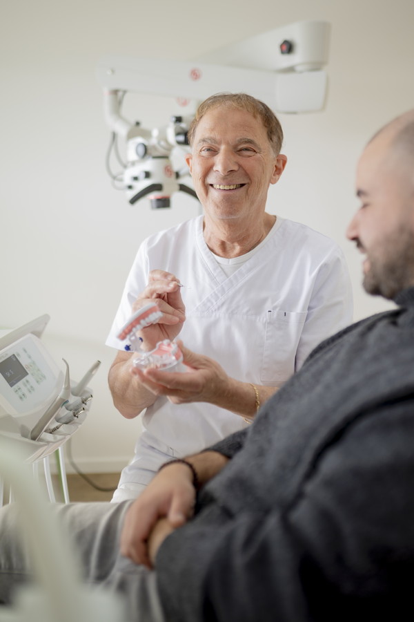 Zahnarzt zeigt einem Patienten ein Gebissmodell in der Praxis