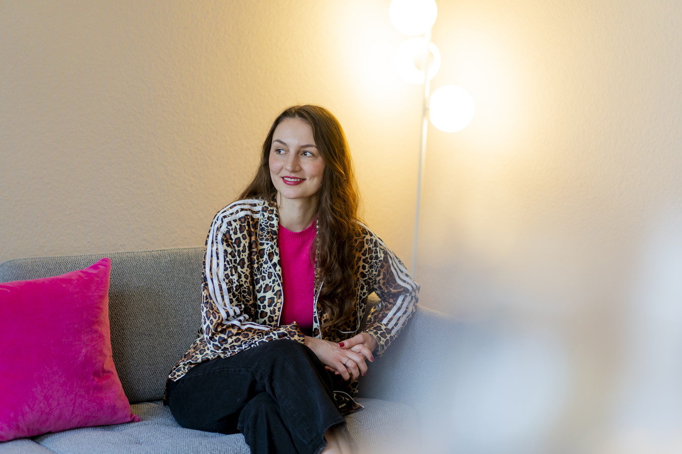 Frau sitzt auf einem Sofa neben einer pinken Kissen und einer Stehlampe