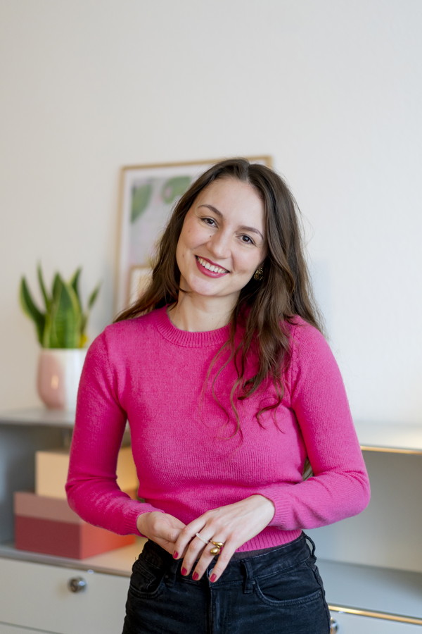 Lächelnde Frau in pinkem Pullover in einem hellen Raum