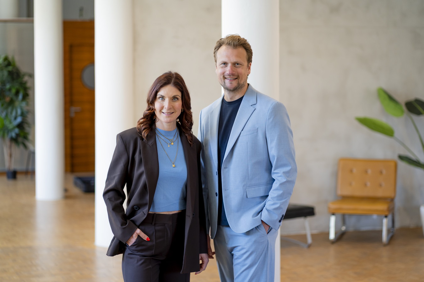Businessportraits Zwei lächelnde Personen in eleganter Kleidung stehen in einem hellen Innenraum