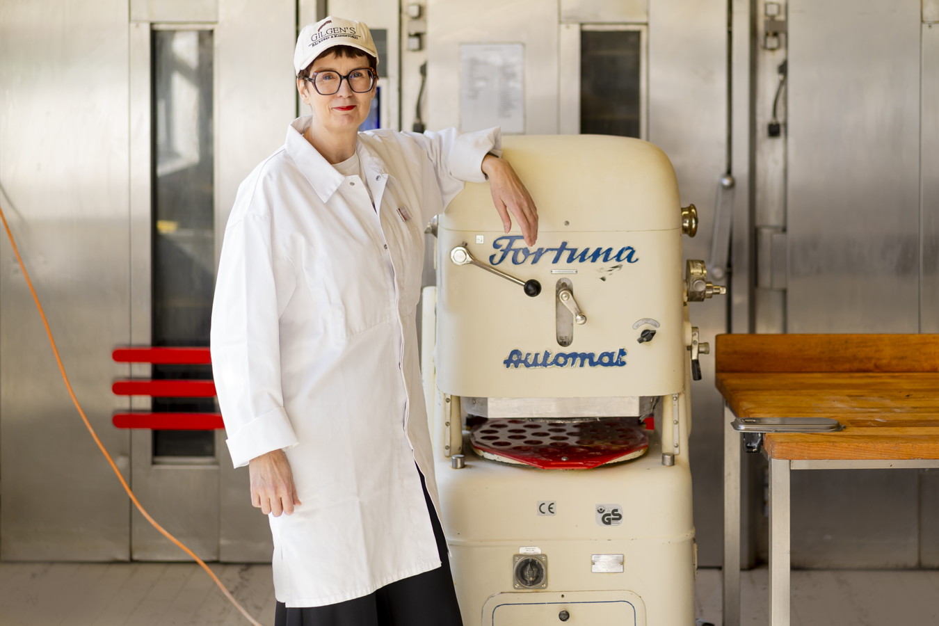 Bäckerin in weißem Kittel neben einer Teigknetmaschine in der Backstube