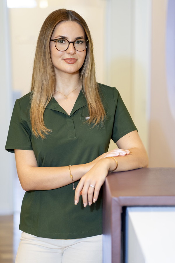 Porträt einer Frau mit Brille in grünem Oberteil, die an einem Tresen lehnt