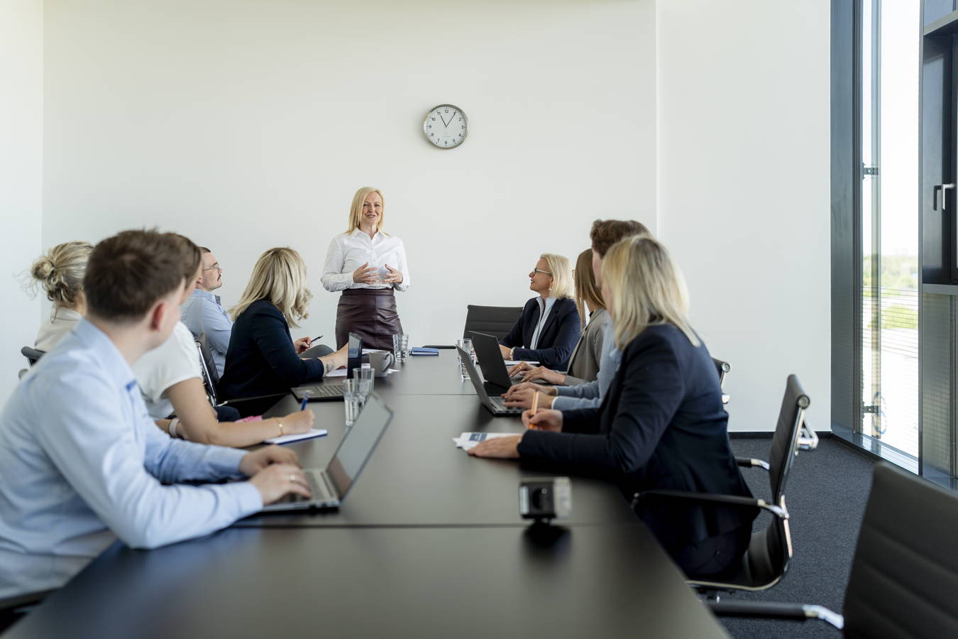 Besprechung in einem Konferenzraum: Eine Frau hält eine Präsentation vor mehreren sitzenden Kollegen