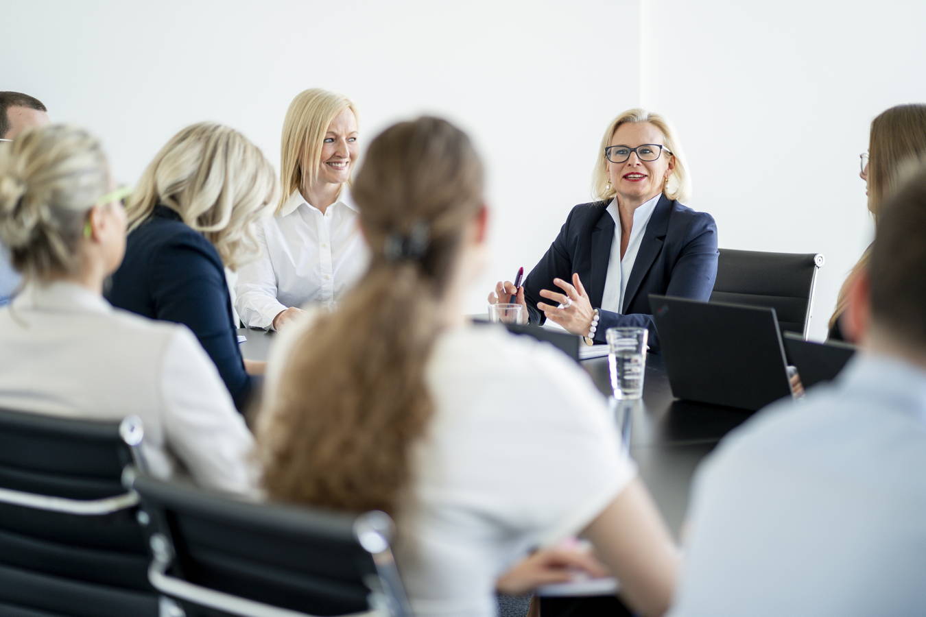 Frauen in einer Besprechung am Konferenztisch, eine spricht vor der Gruppe