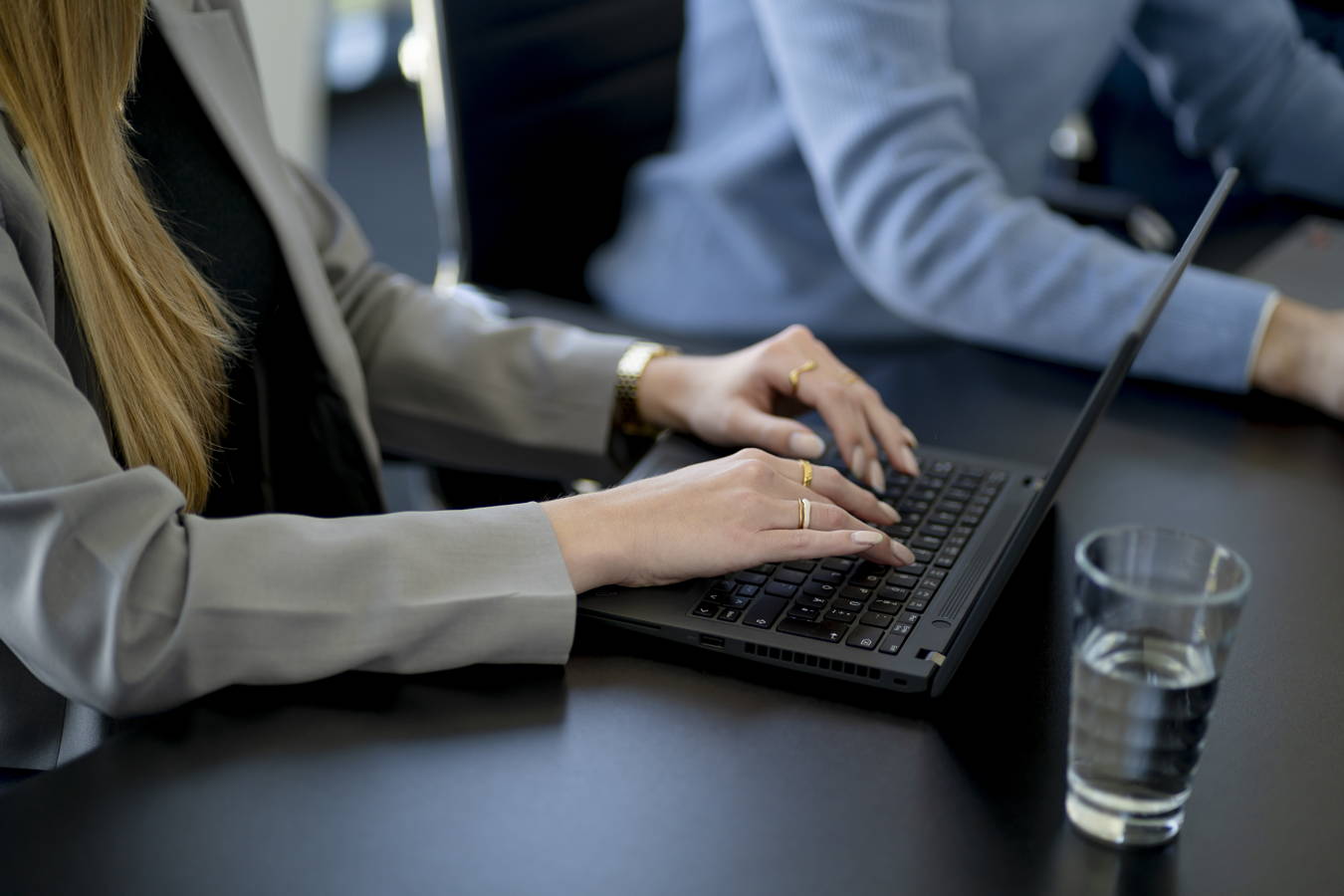 Frau tippt an einem Laptop im Besprechungsraum