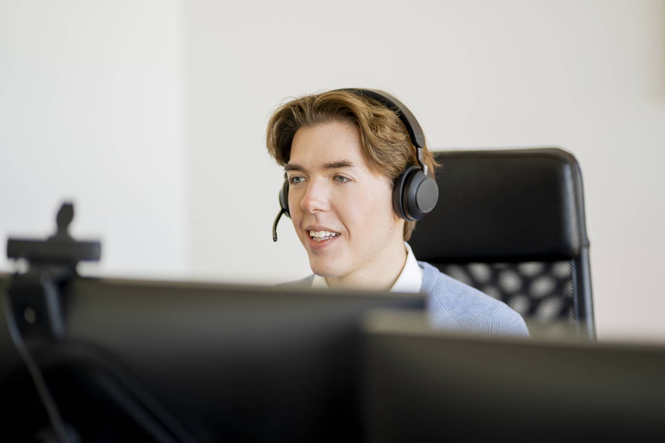 Mann mit Headset sitzt am Computer und spricht
