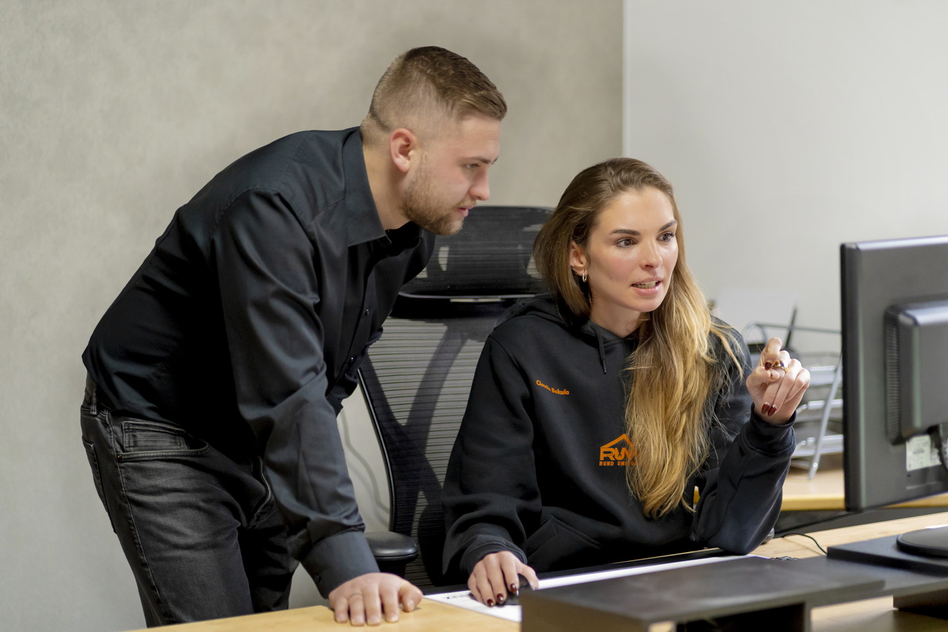 Zwei Kollegen besprechen etwas am Computer im Büro