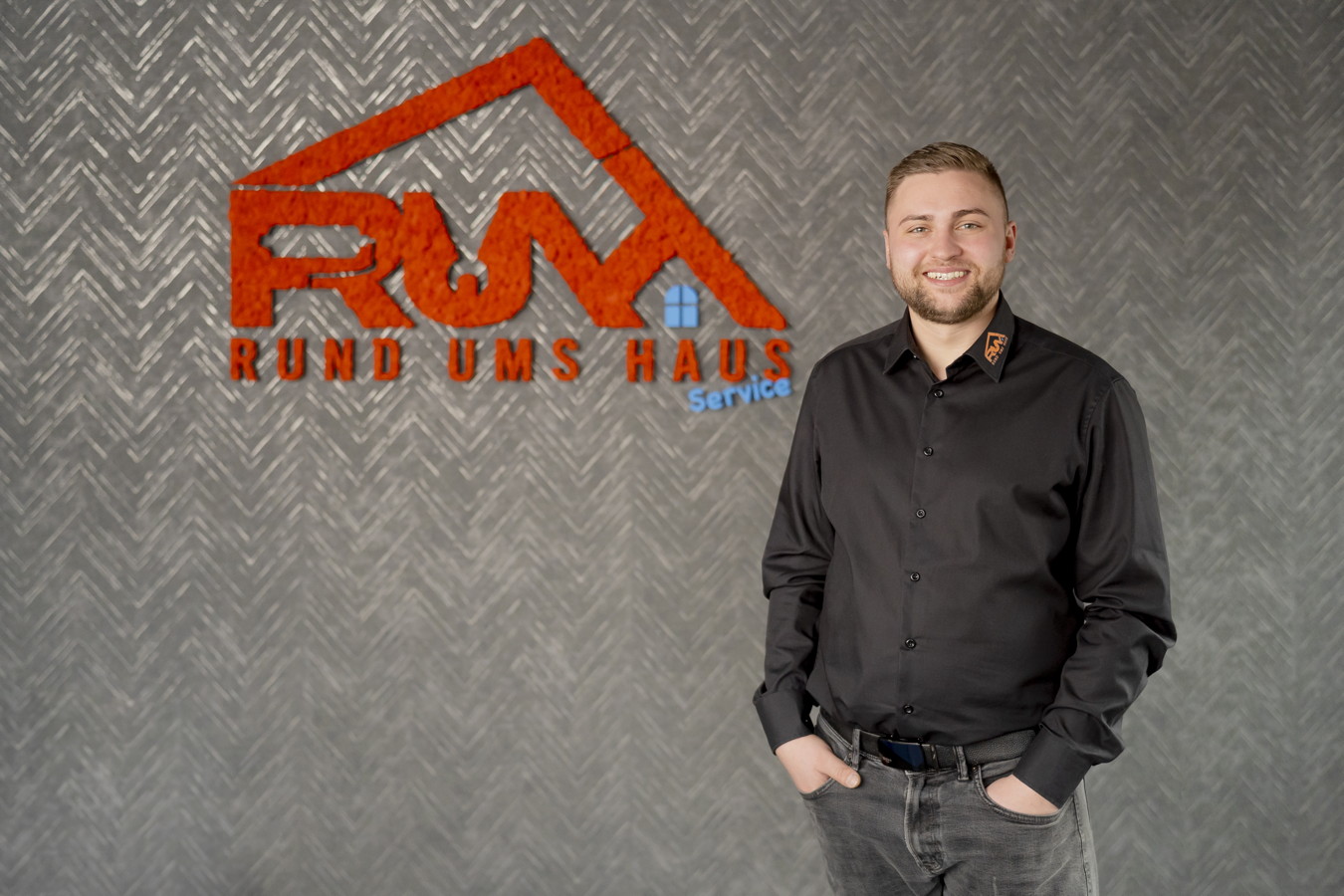 Mitarbeiter vor dem Logo von Rund Ums Haus Service