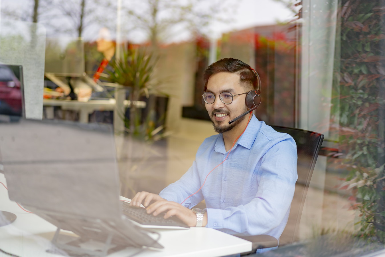 Mann mit Headset arbeitet am Laptop im Büro