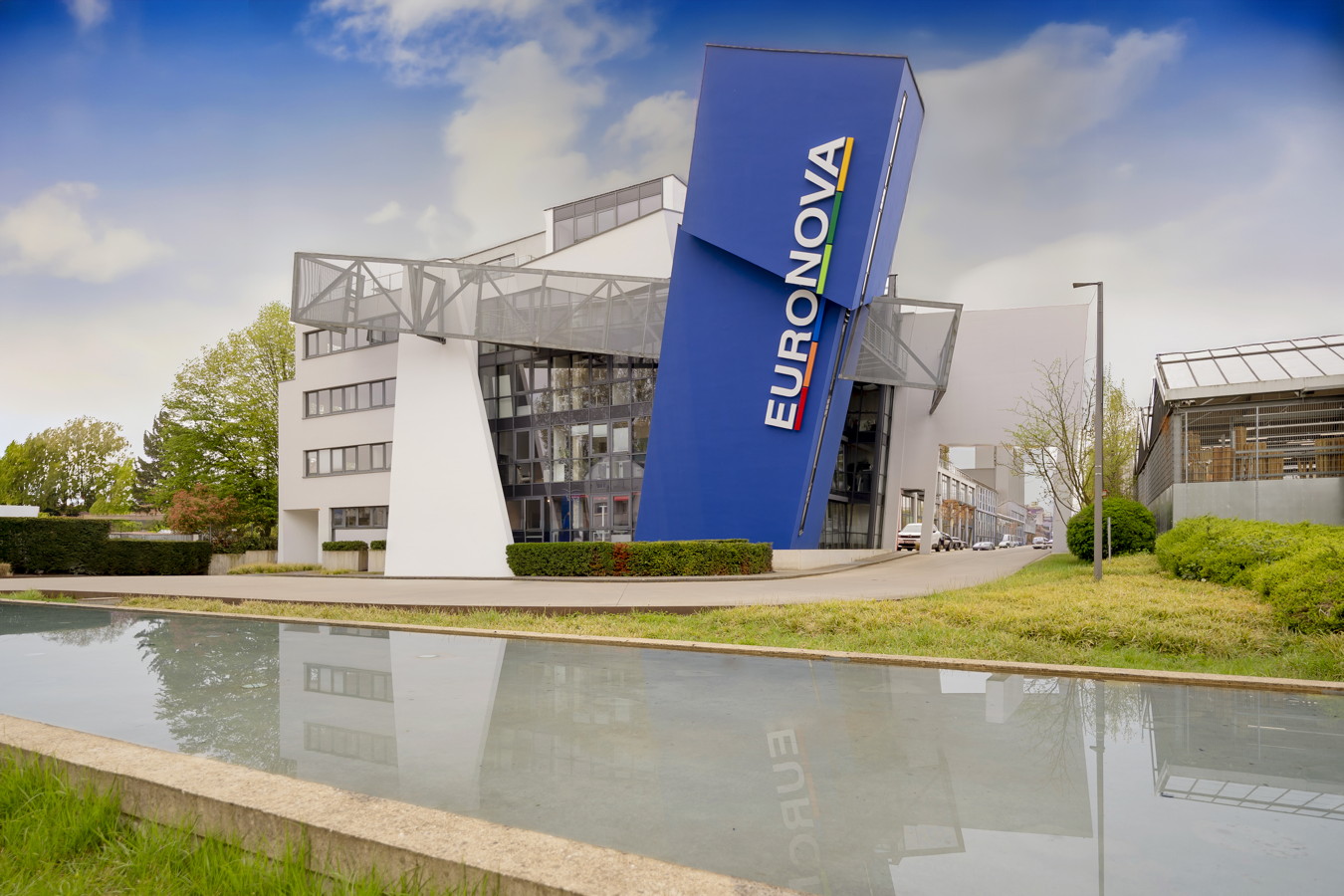 Euromova-Gebäude mit großem blauem Firmenschild vor einem Wasserbecken