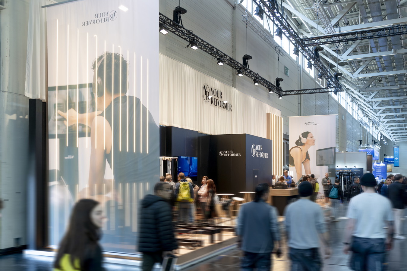 Messestand von Your Reformer auf einer Messehalle mit Besuchern und großen Werbebannern