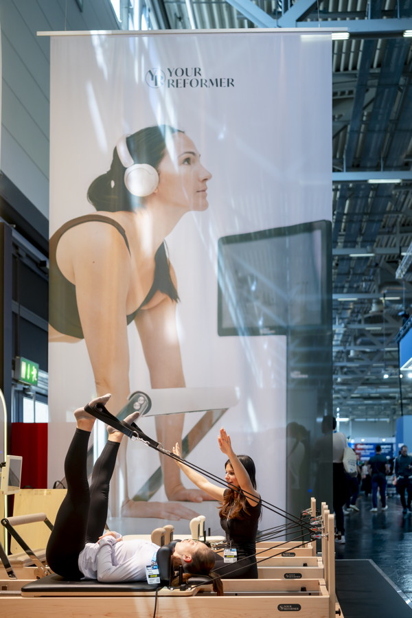 Pilates-Training mit Reformer-Geräten auf einer Messe