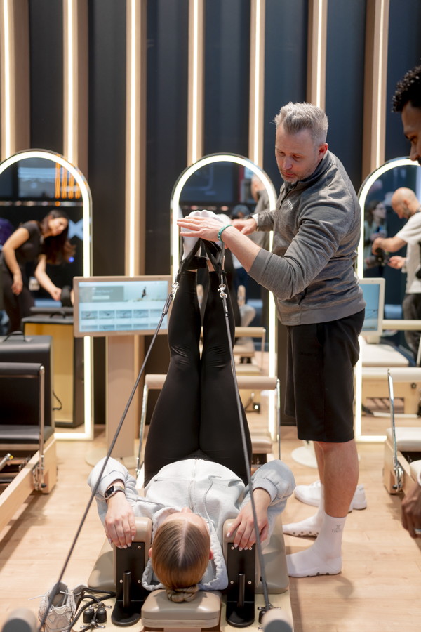 Trainer justiert die Beine einer Person auf einer Pilates-Reformer-Liege